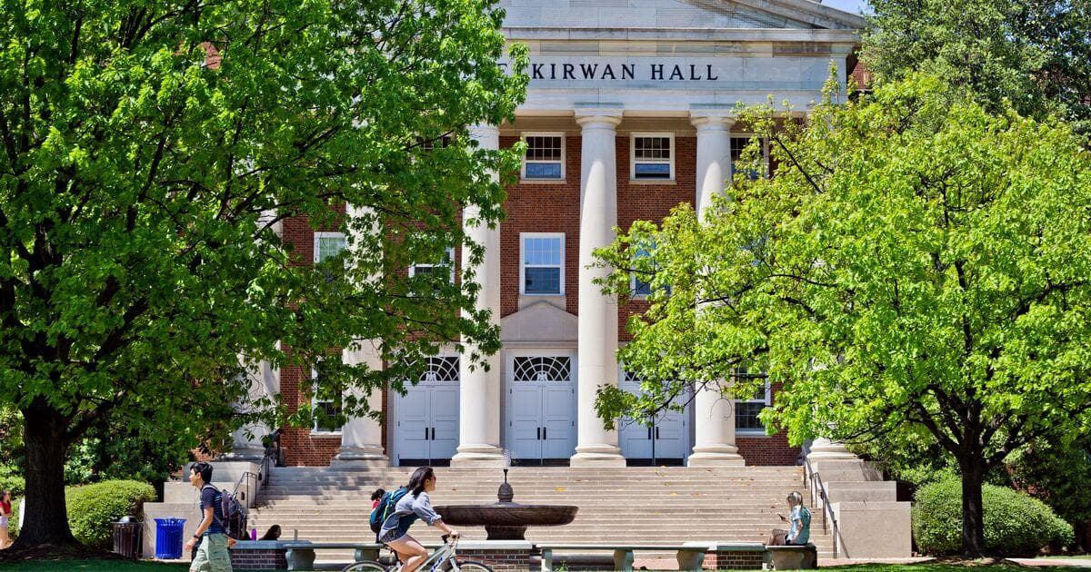 Students walking and riding a bike in front of Kirwan Hall