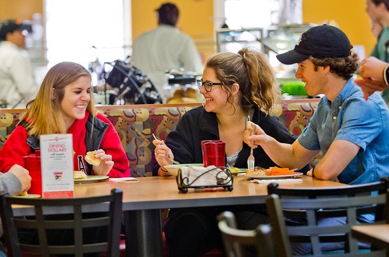 Students laughing and eating at dining hall