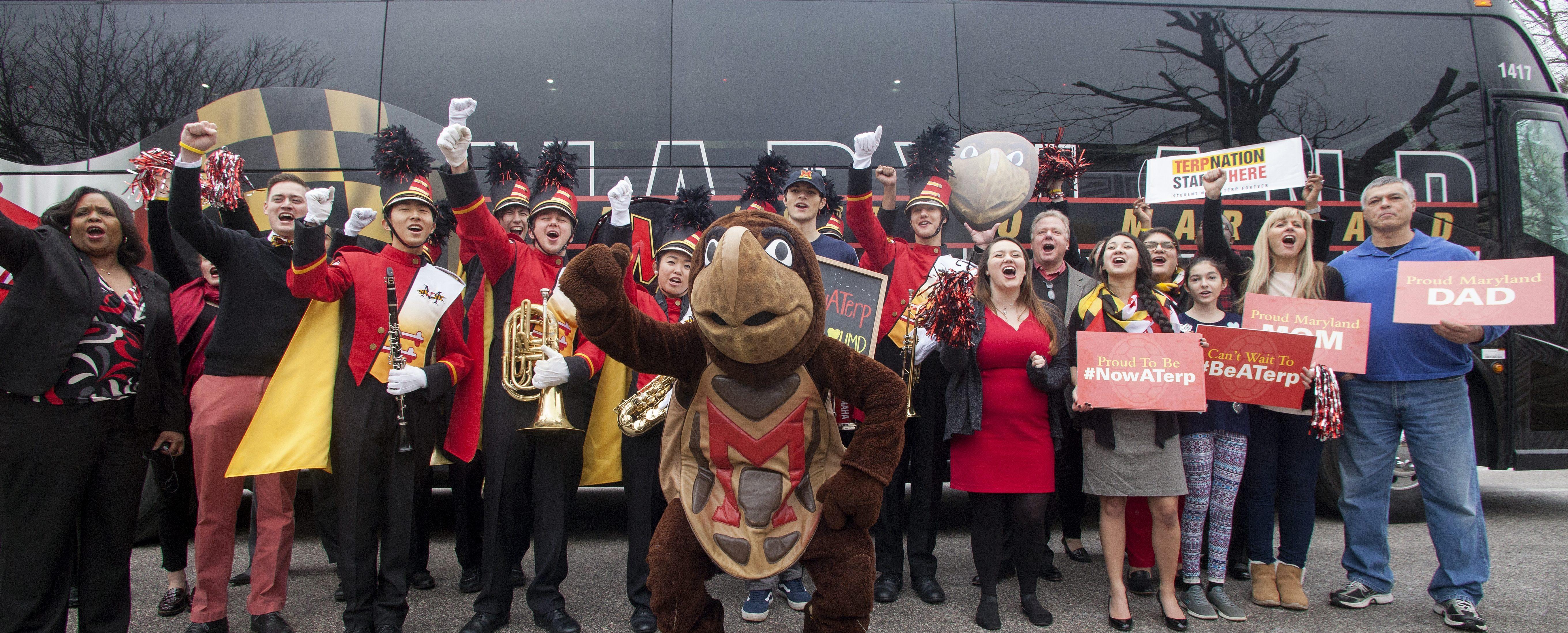 Crowd cheering in front of a University of Maryland bus.