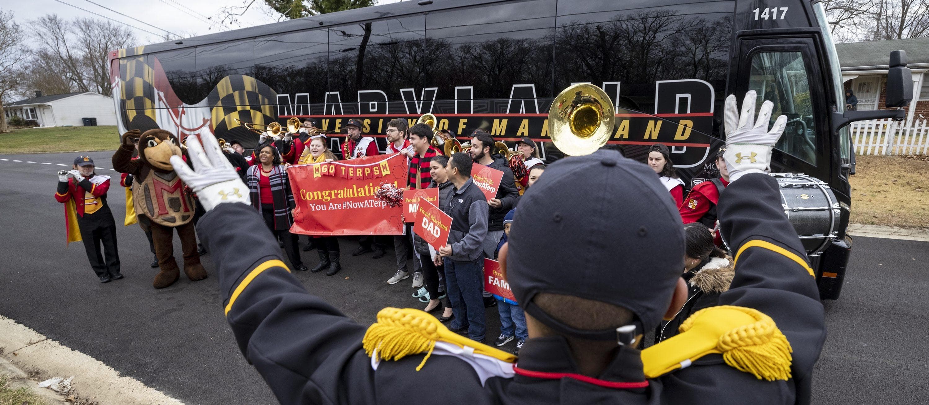 Band conductor standing in front of cheering crowd.